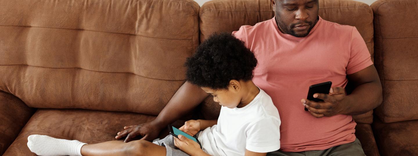 Man sitting with child uses phone