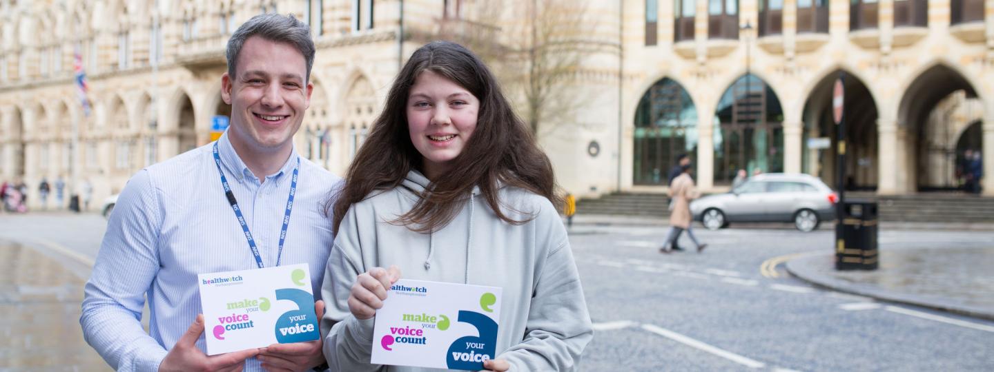 Young adult male volunteer with young female volunteer holding promotional material
