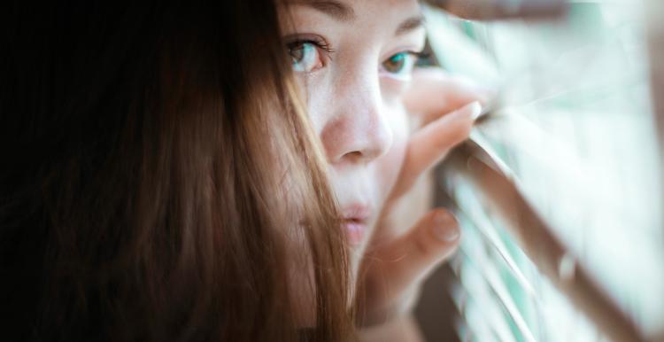 woman alone at home peeking through the blinds