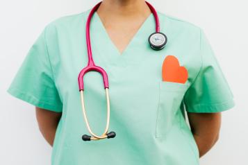 Medic in scrubs with stethoscope and red paper heart